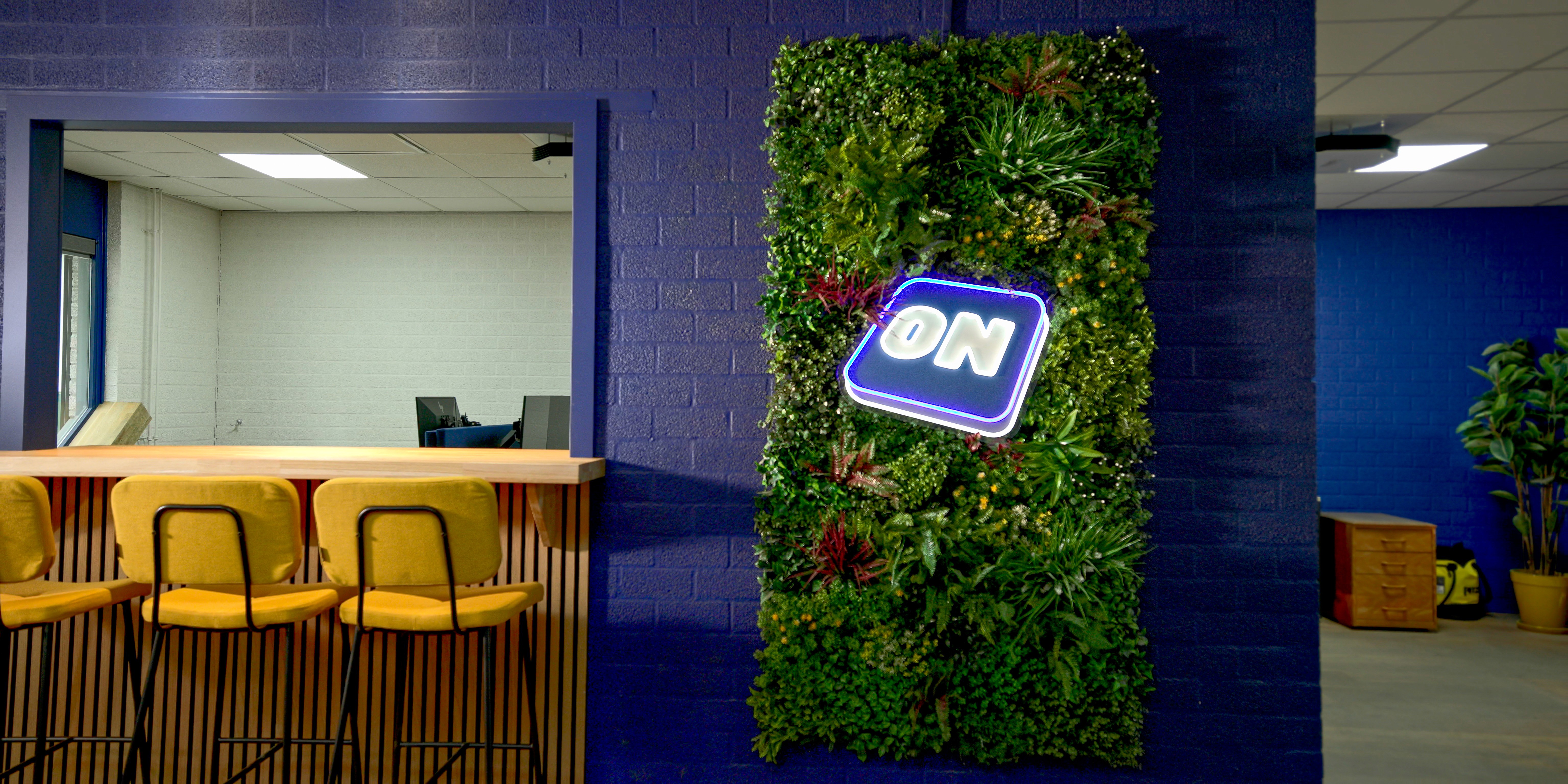 Kantoorruimte Oostendorp Nederland met bar, gele barkrukken, groene plantenwand en ON-logo, ingericht door DSN Workspace Solutions