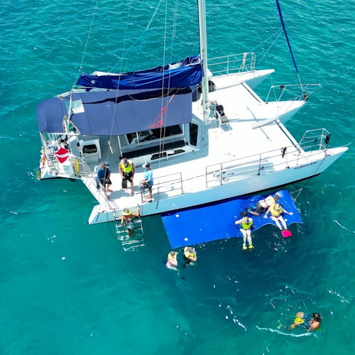 客人在瓦胡岛清澈的蓝色海水中，乘坐霍库拉尼双体船放松和浮潜。