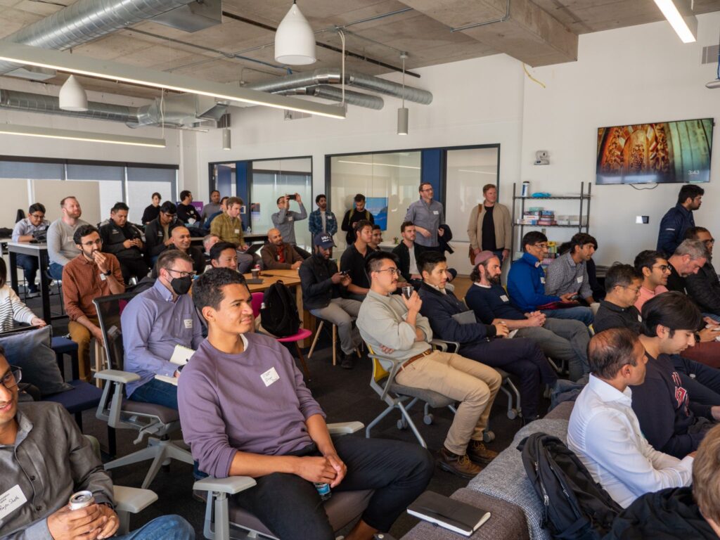 a group of people sitting, paying close attention to a speaker at the conference