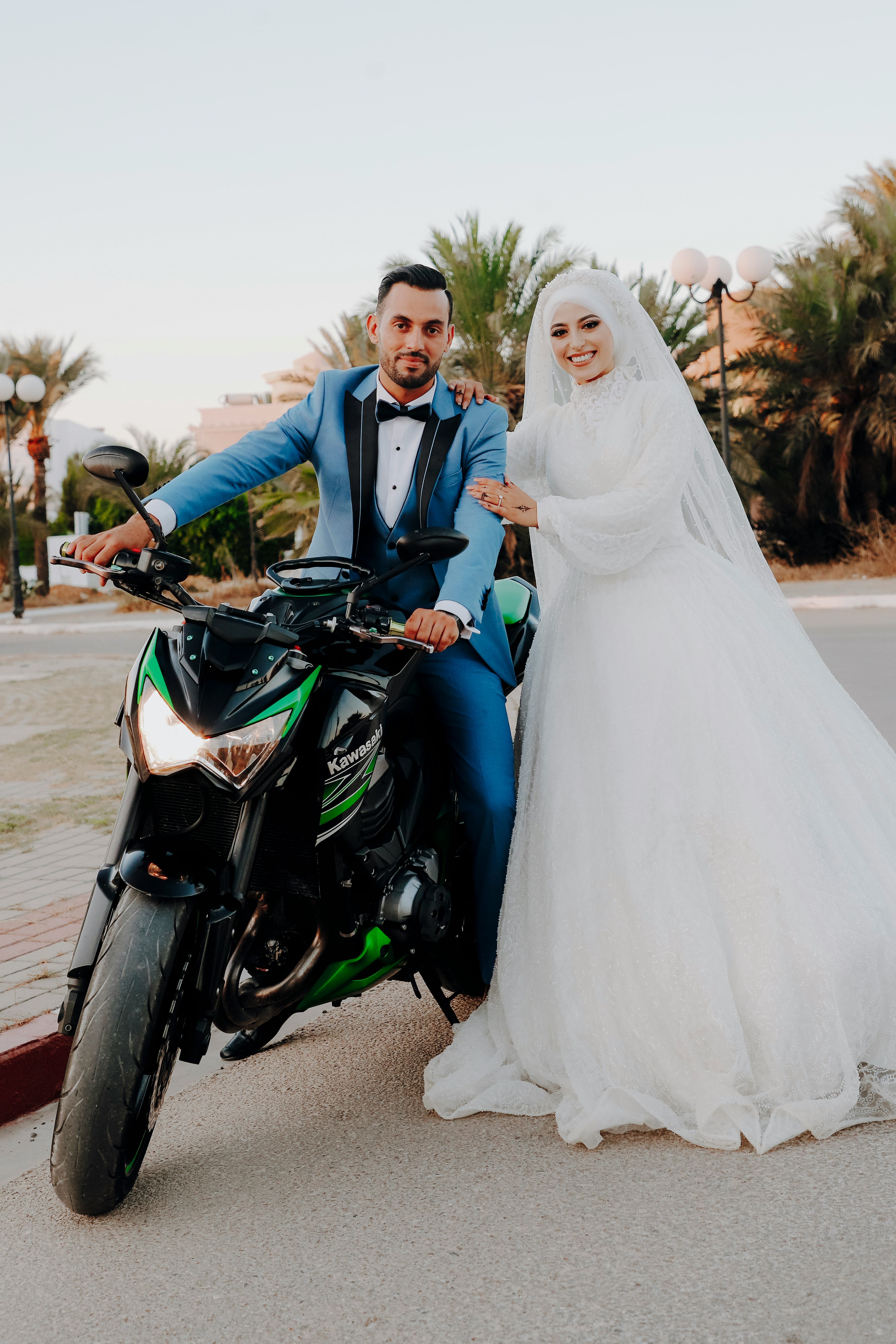 a bride and groom pose on a motorcycle