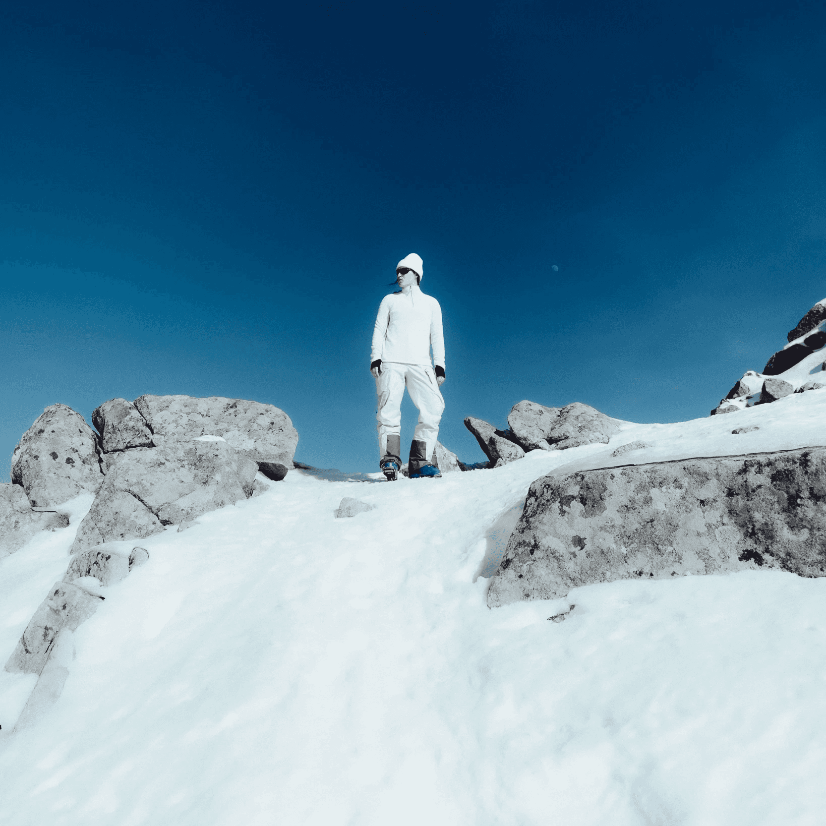picture of a model standing on a rock covered in snow.