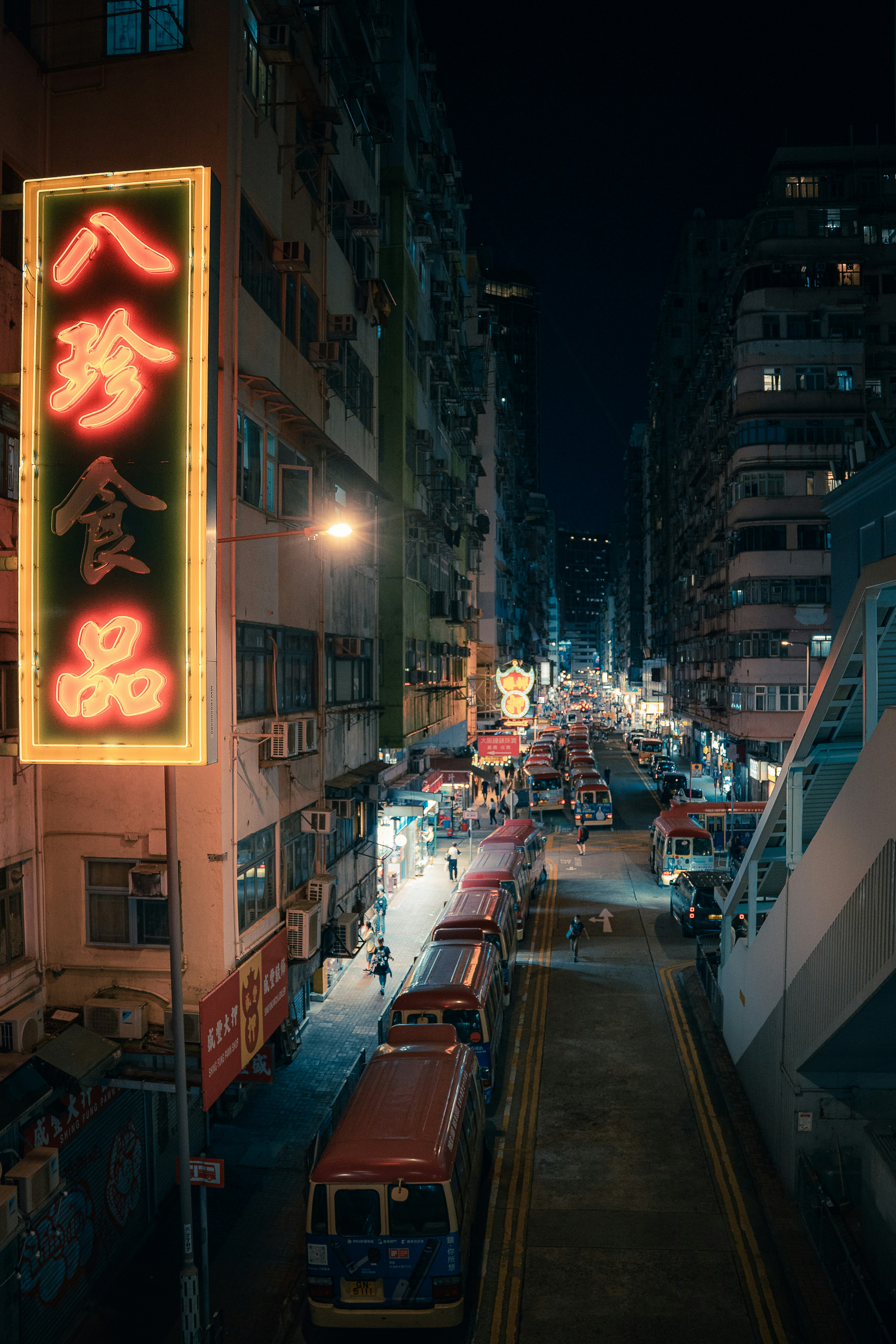 Neon signs illuminate a busy street at night.