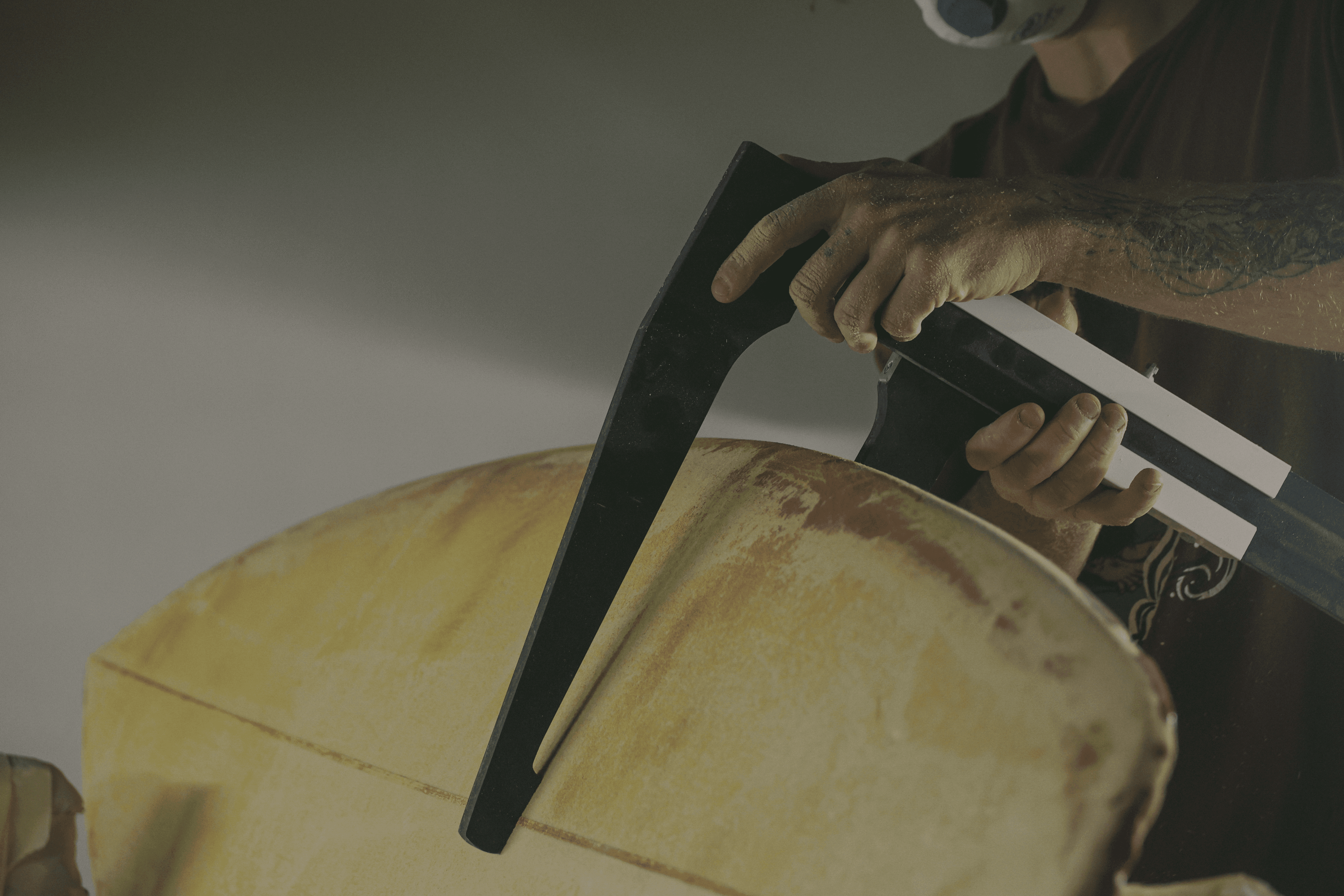 Shaper artigiano al lavoro sulla resinatura di una tavola da surf personalizzata.