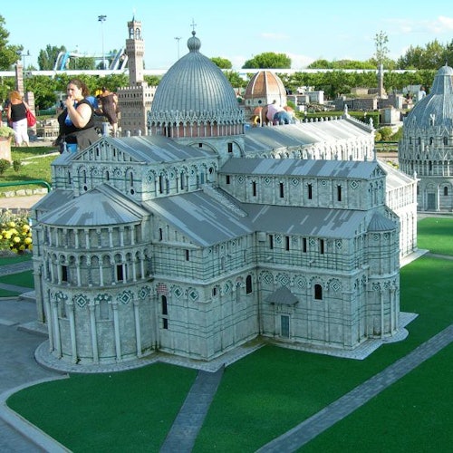 A detailed model of a historic multi-domed building with people in the background enjoying a park on a sunny day.