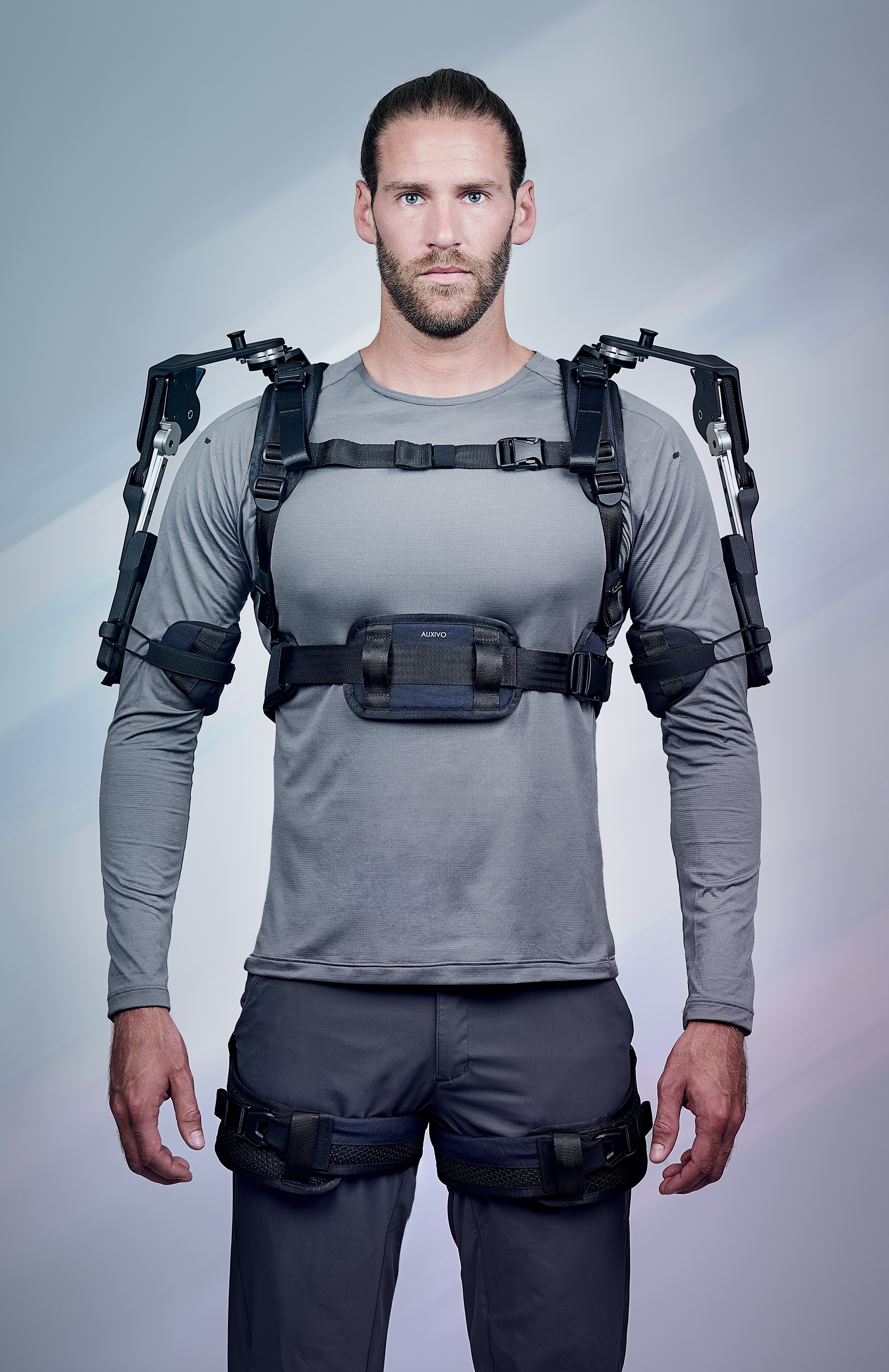 Front view of the Auxivo OmniSuit exoskeleton worn by a worker, with articulated arms providing assistance to the shoulders and back.