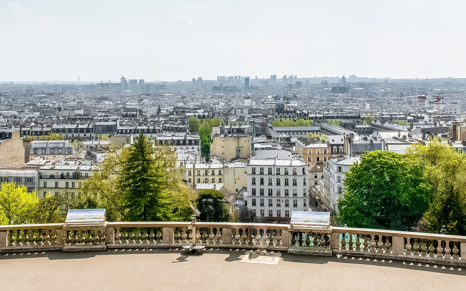 Tanawin ng skyline ng Paris mula sa Montmartre, tampok ang tanawin ng lungsod at luntiang kapaligiran.