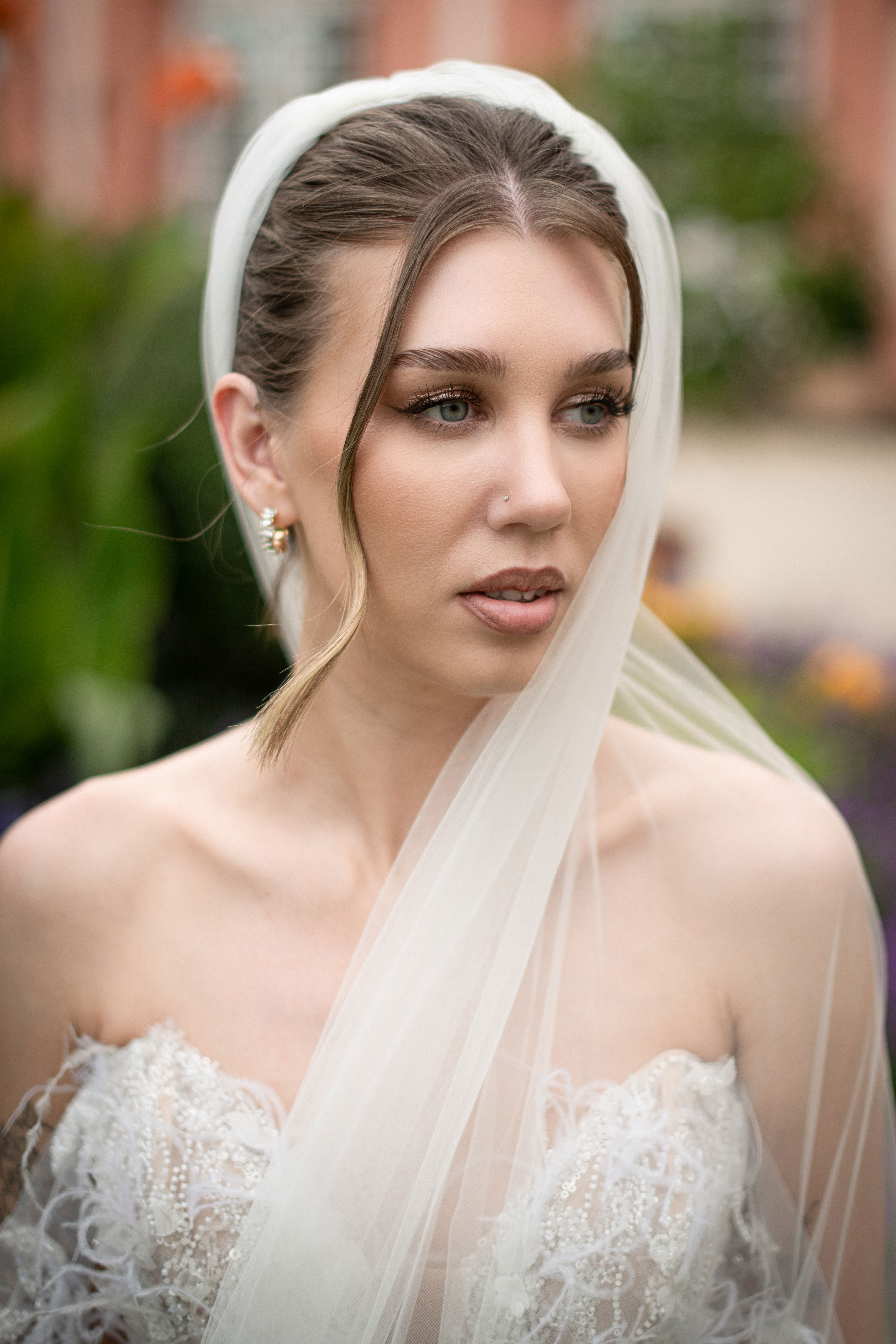 Eine Braut posiert in einem verspielten Hochzeitskleid in einem Garten.