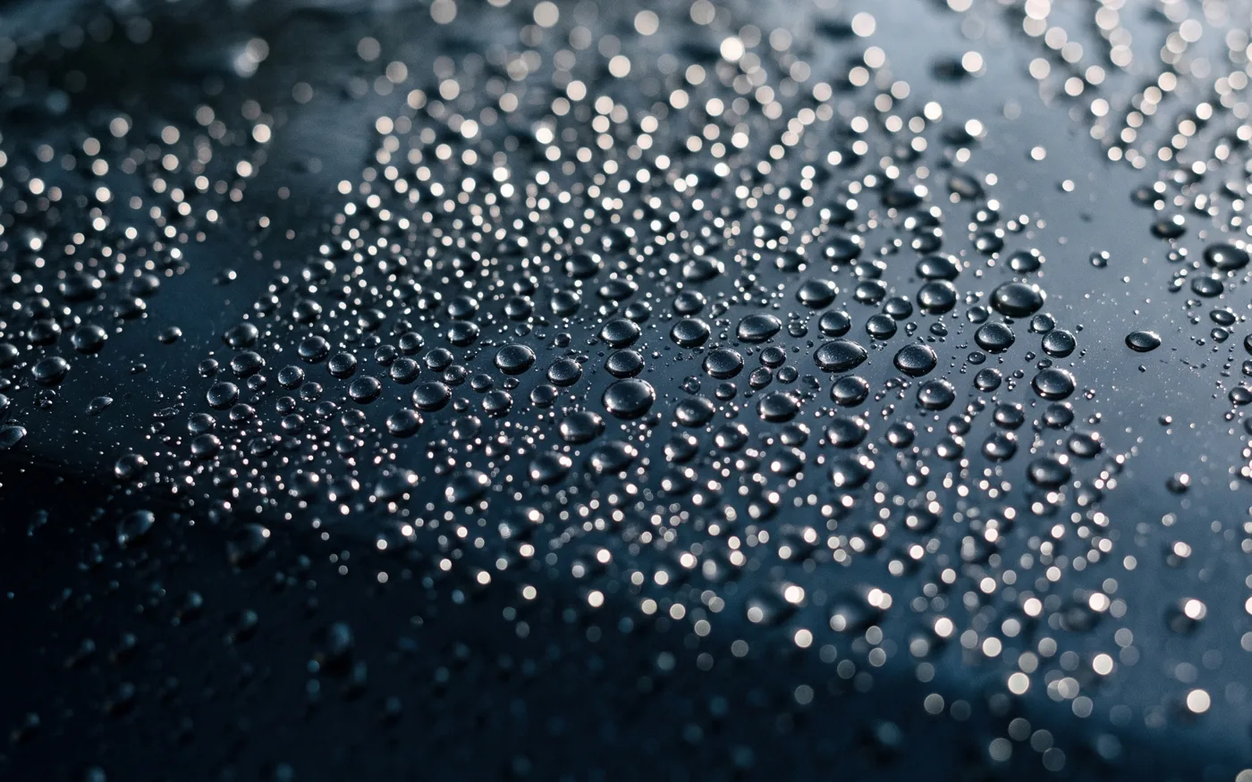 Water beads on dark navy paint, close up