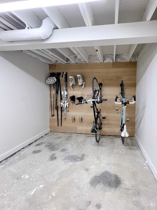 Image of Bicycles and sports equipment stored in a garage with wood paneling and exposed ceiling beams KHD.
