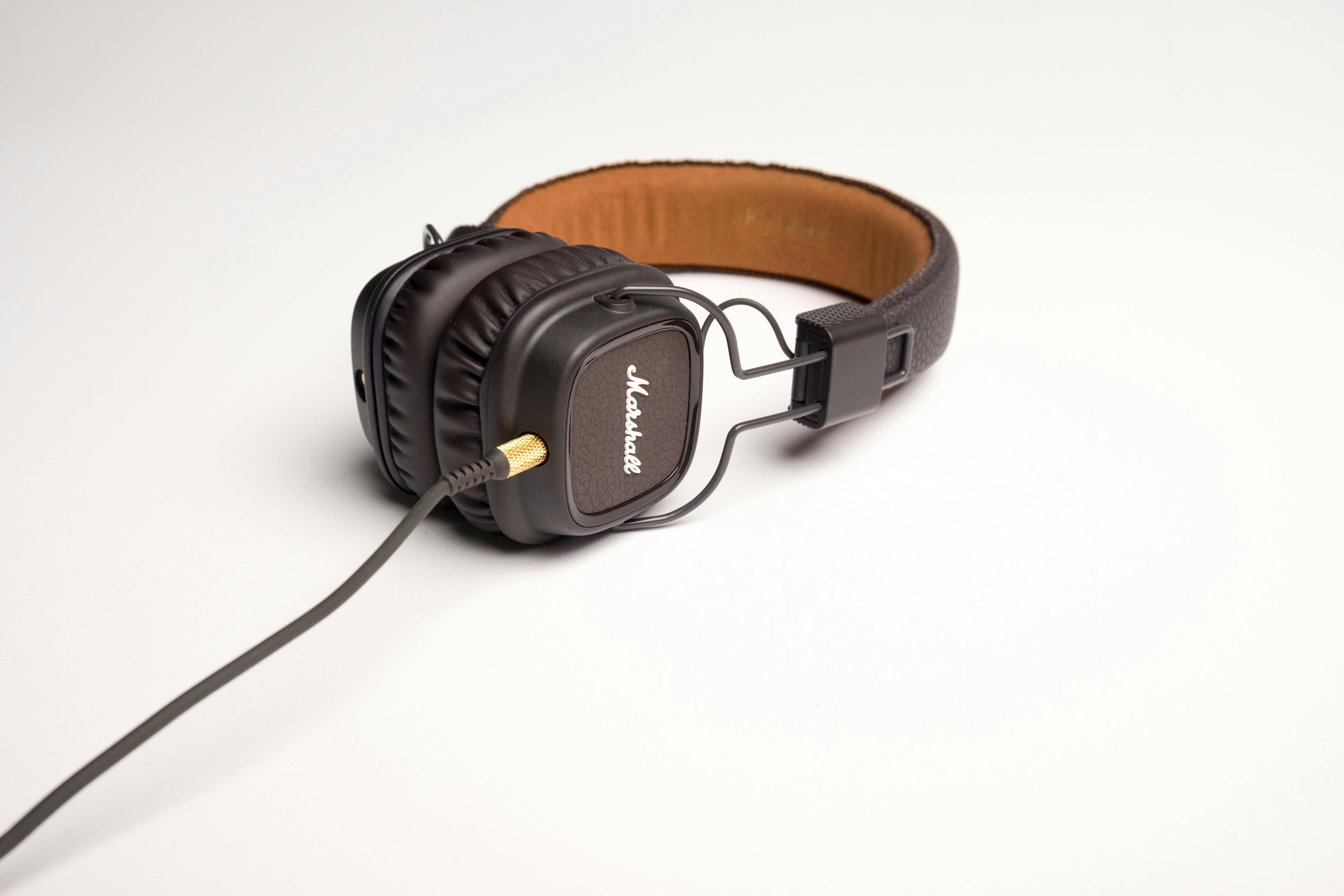 A pair of marshall headphones rests on a surface.