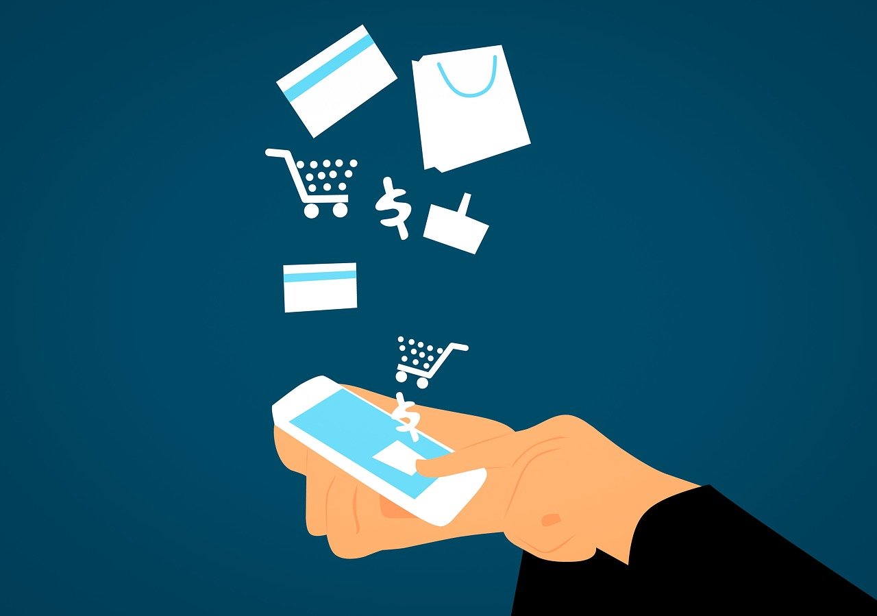 Blauer Hintergrund auf dem eine stilisierte Hand auf ein Smartphone tippt, aus dem Icons fliegen, die E-Commerce beschreien sollen, zB. ein Dollarzeichen, eine Einkaufstasche usw.