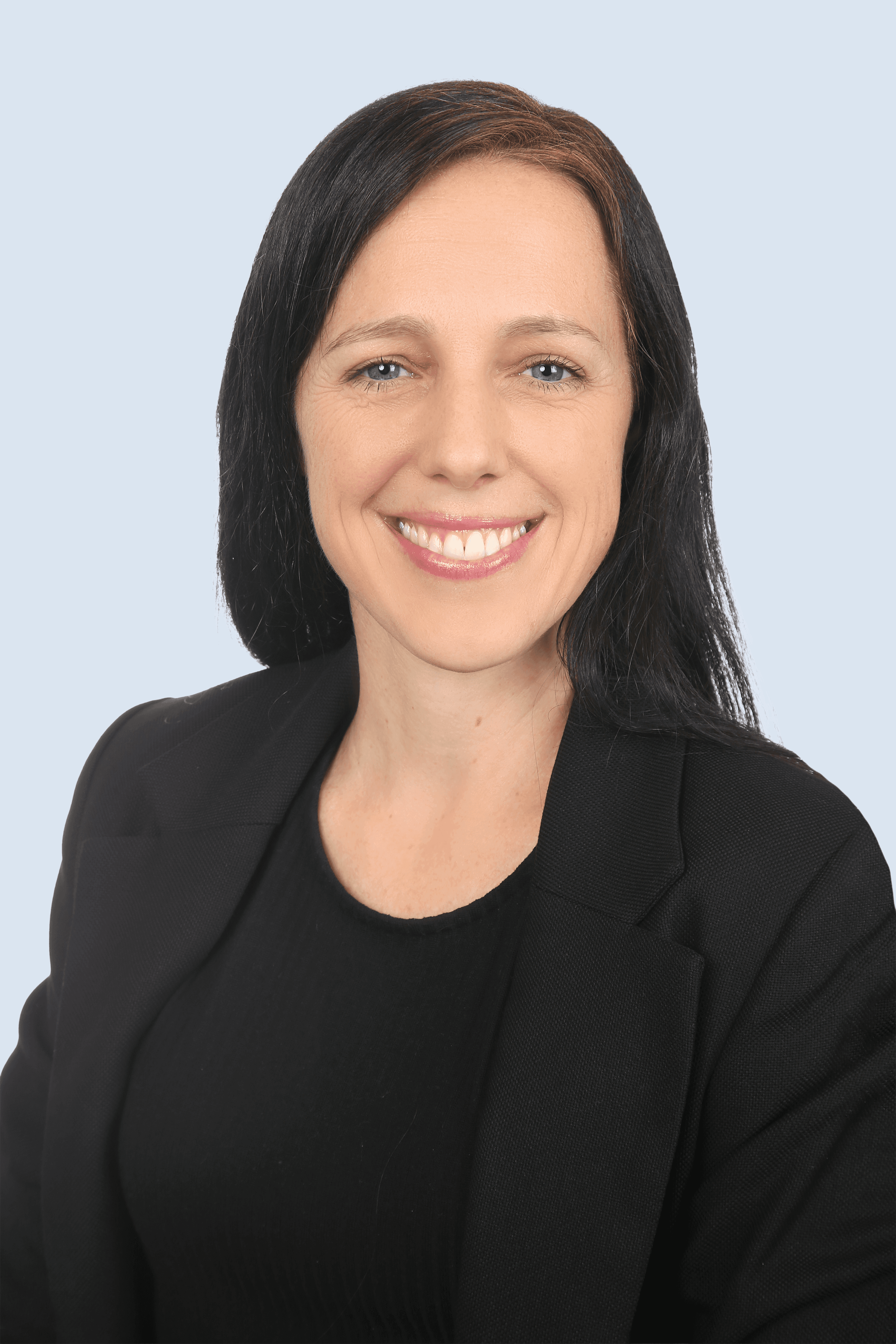 Frau mit schwarzem Anzug und rotem Hemd schaut in die Kamera und lächelt. Sie hat die Arme verschränkt. (Background Removed)