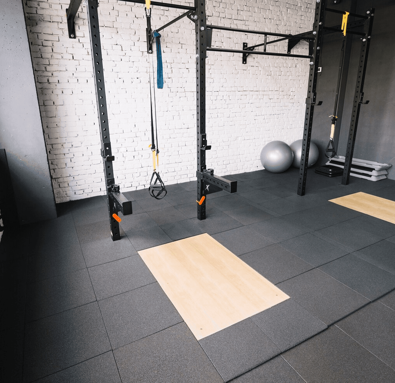 Empty modern gym with squat racks, suspension straps, and lifting platforms.
