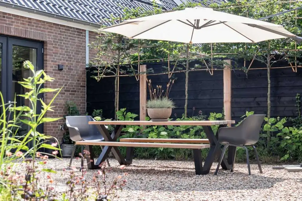 Tuin van de woonboerderij met picknicktafel en parasol