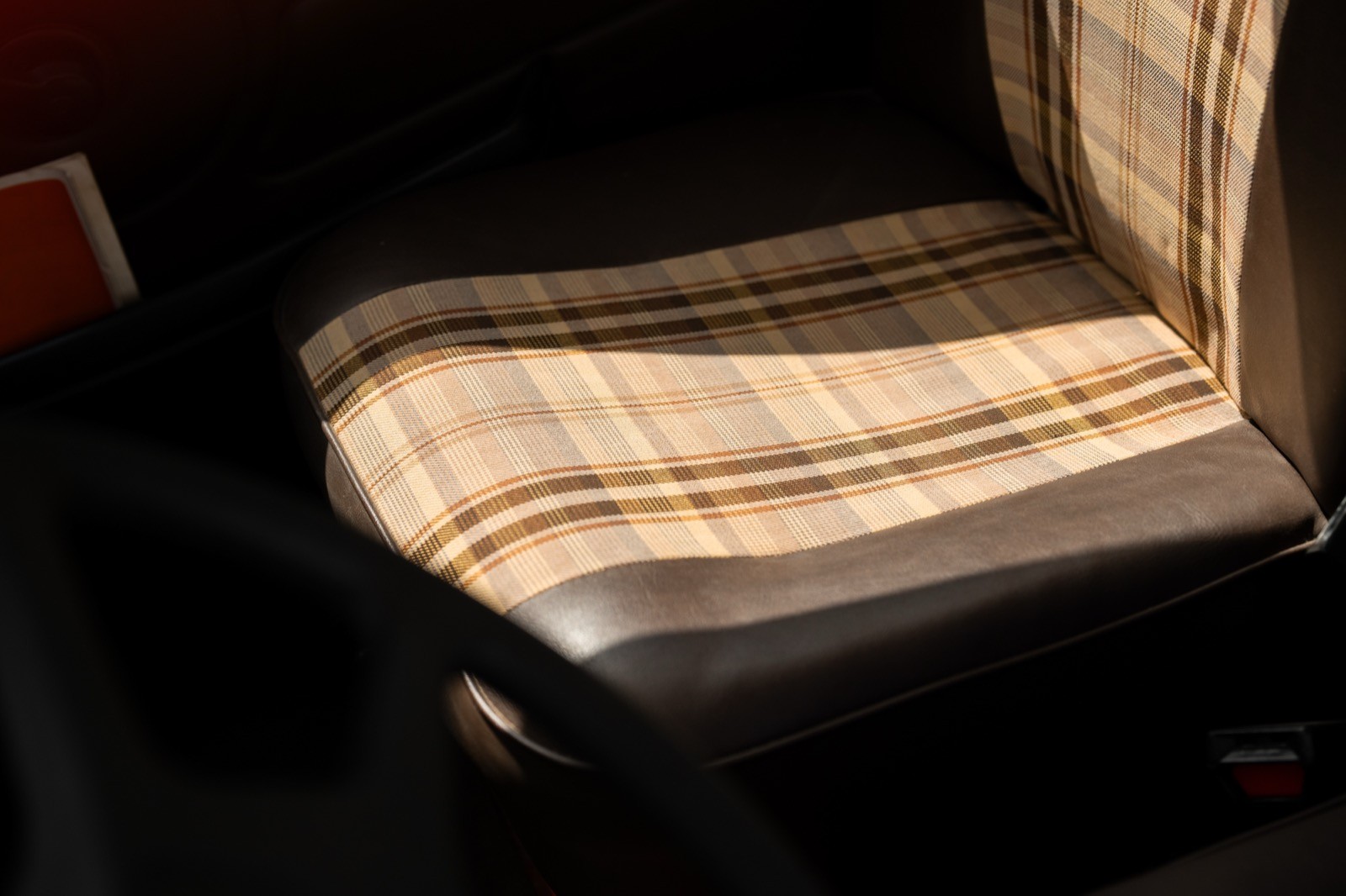 Close-up of a car seat with a patterned fabric cover and shadowing from sunlight.