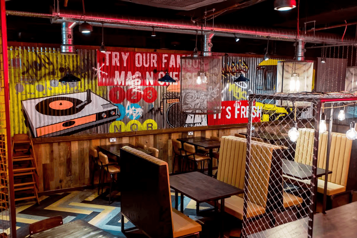 Holy Moly Macaroni restaurant fit-out at Grand Central Birmingham with branded wall graphics, feature lighting and bespoke interior detailing by Matrix IDC