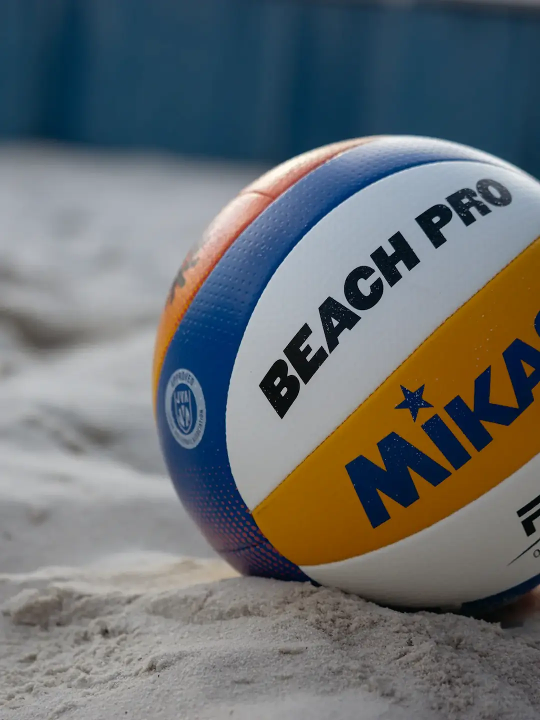 Beachvolejbalový míč Mikasa, který leží na písku hřiště.