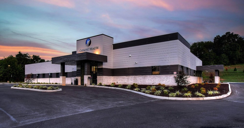 Modern architectural building with unique design, illuminated at dusk with a colorful sky in the background.