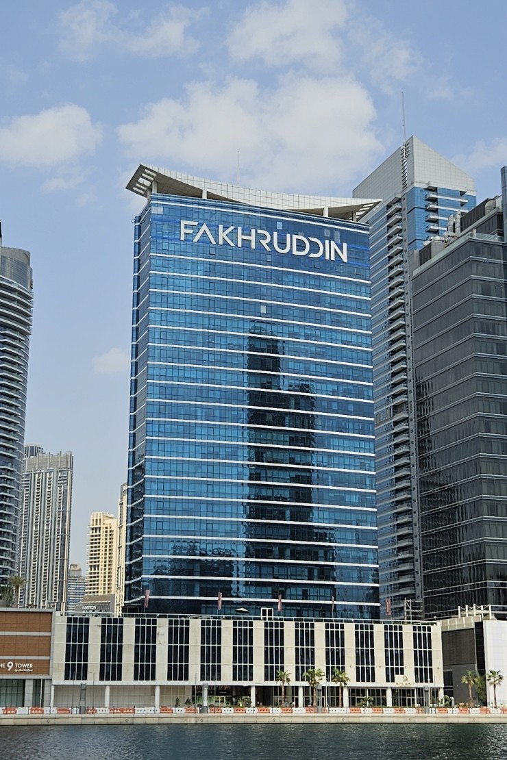 Full view of Lake Central Tower's glass facade reflected in the Business Bay canal waters.