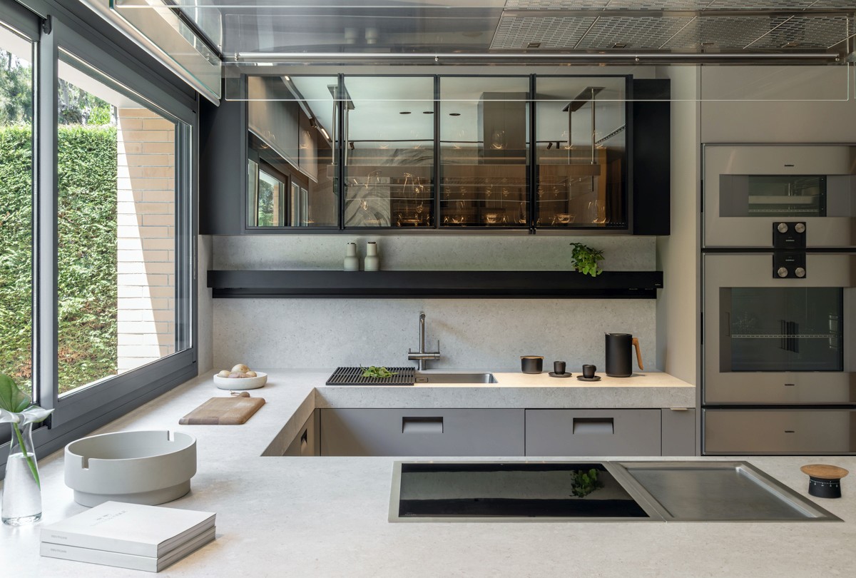 Cocina Arclinea con muebles y encimera en tonos grises y ventana grande al jardín