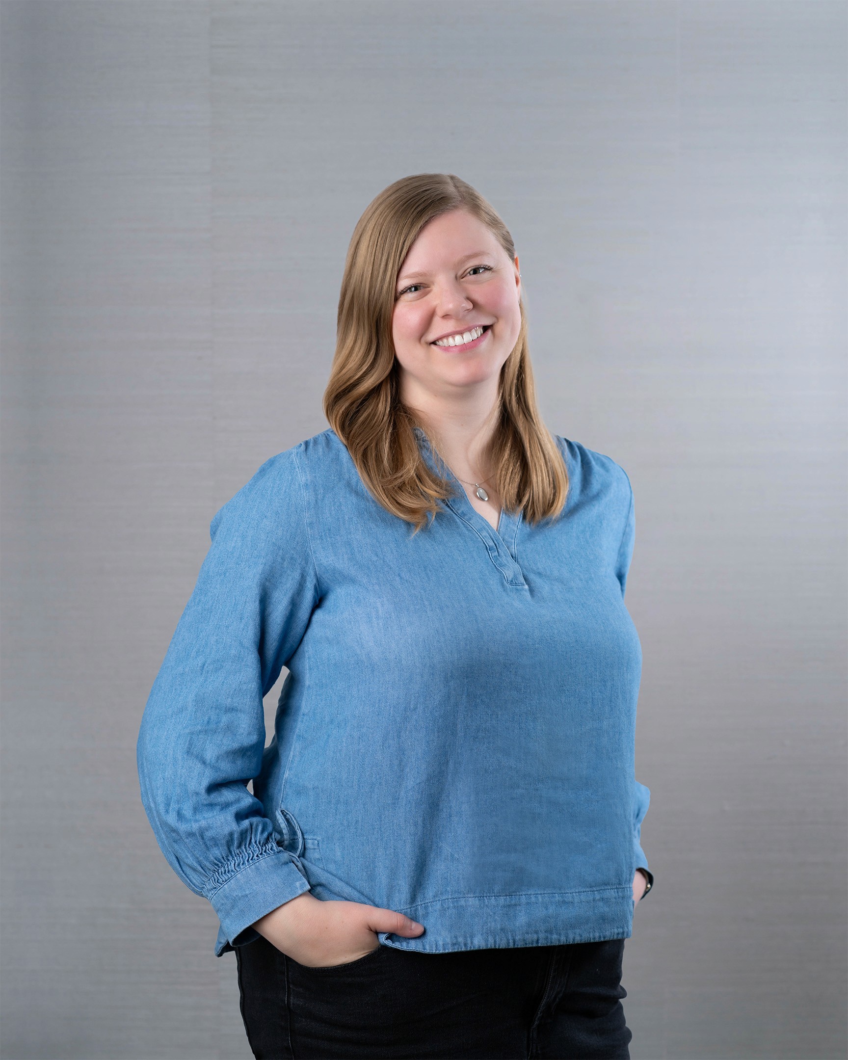 Friendly blond woman wearing long sleeve blue shirt.