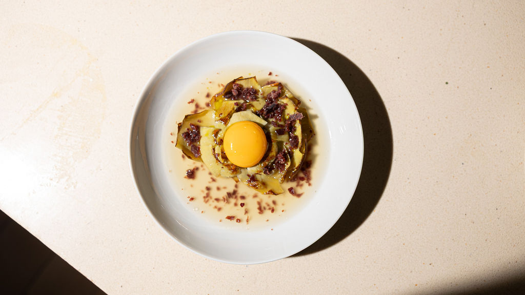 Freshly baked Margherita pizza with melted cheese, tomato sauce, and basil leaves, held by a person’s hand.