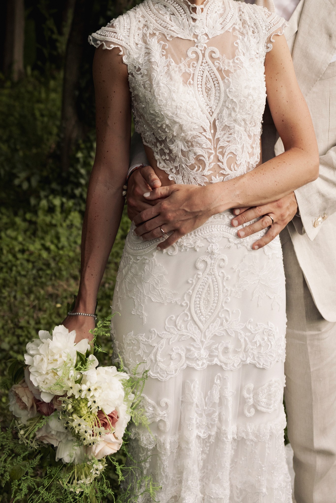 Sposa in abito di pizzo bianco con bouquet, mani intrecciate dello sposo, ritratto di matrimonio alla Rocca di Soragna