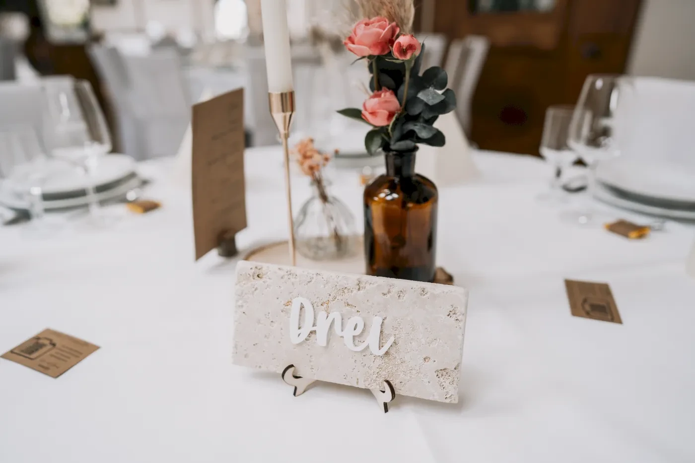 Dekorierter Hochzeitstisch mit Blumen und Namensschild "Drei", elegante Tischdekoration.