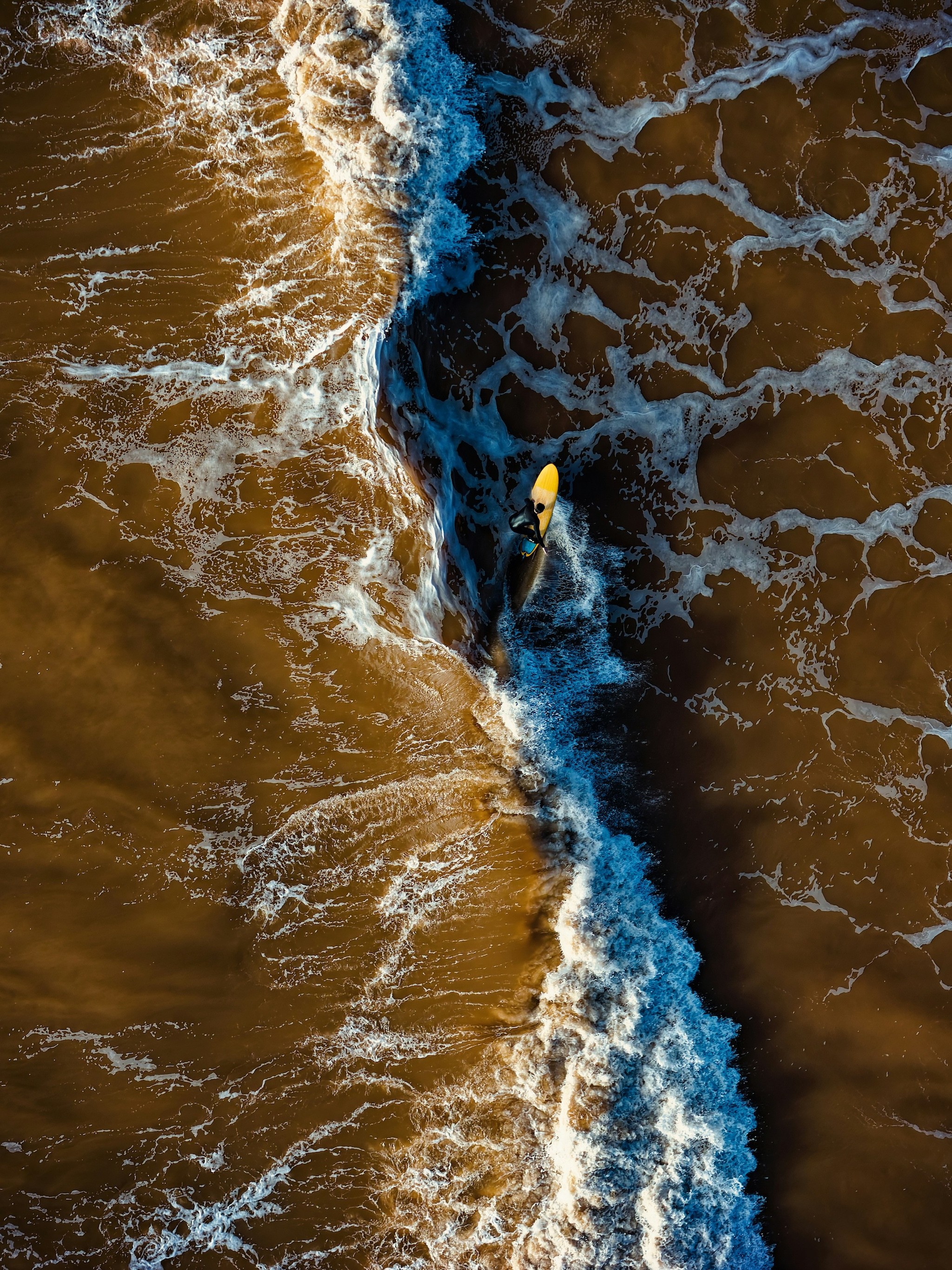 Person in dark cloak stands in glowing orange sandstone canyon