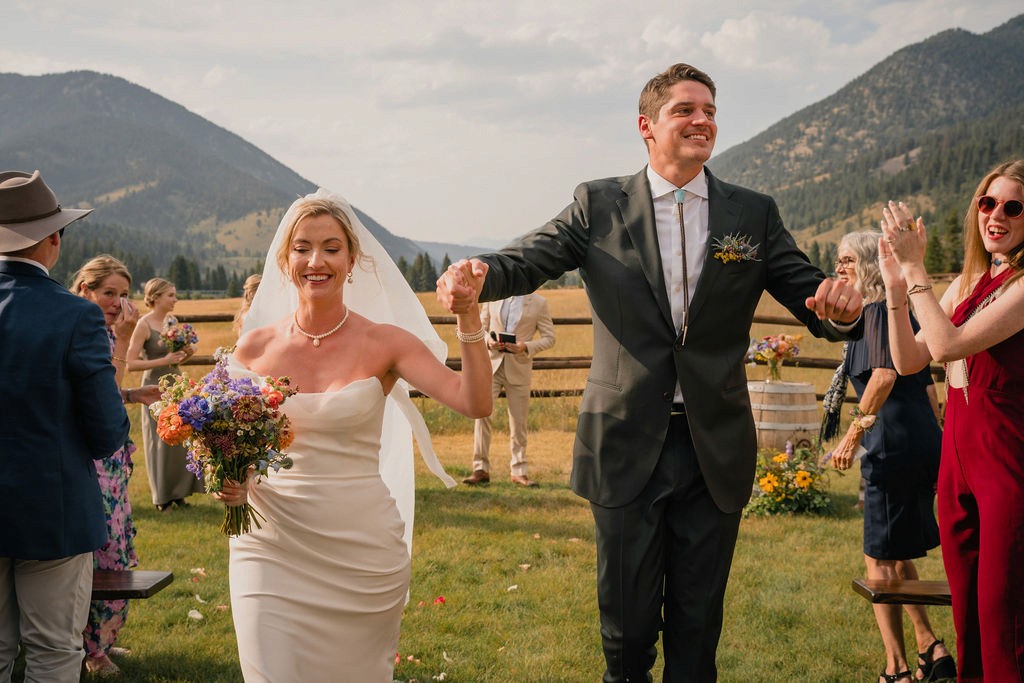 Newlyweds walking up the aisle as guests applaud