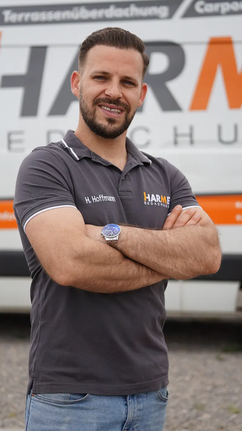 Harmes-Mitarbeiter H. Hoffmann im Poloshirt vor dem Firmenfahrzeug