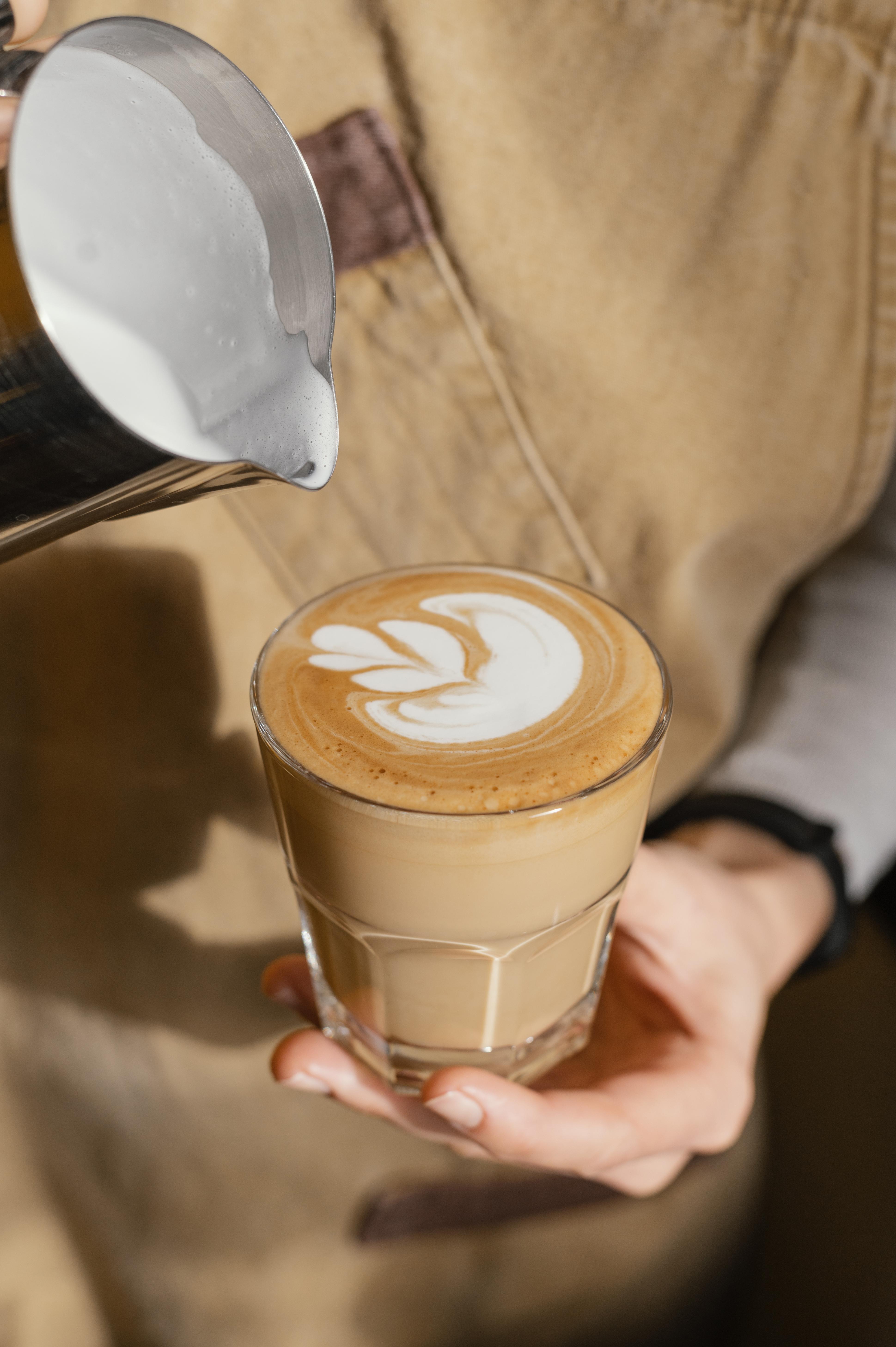Barista pouring milk into latte with art