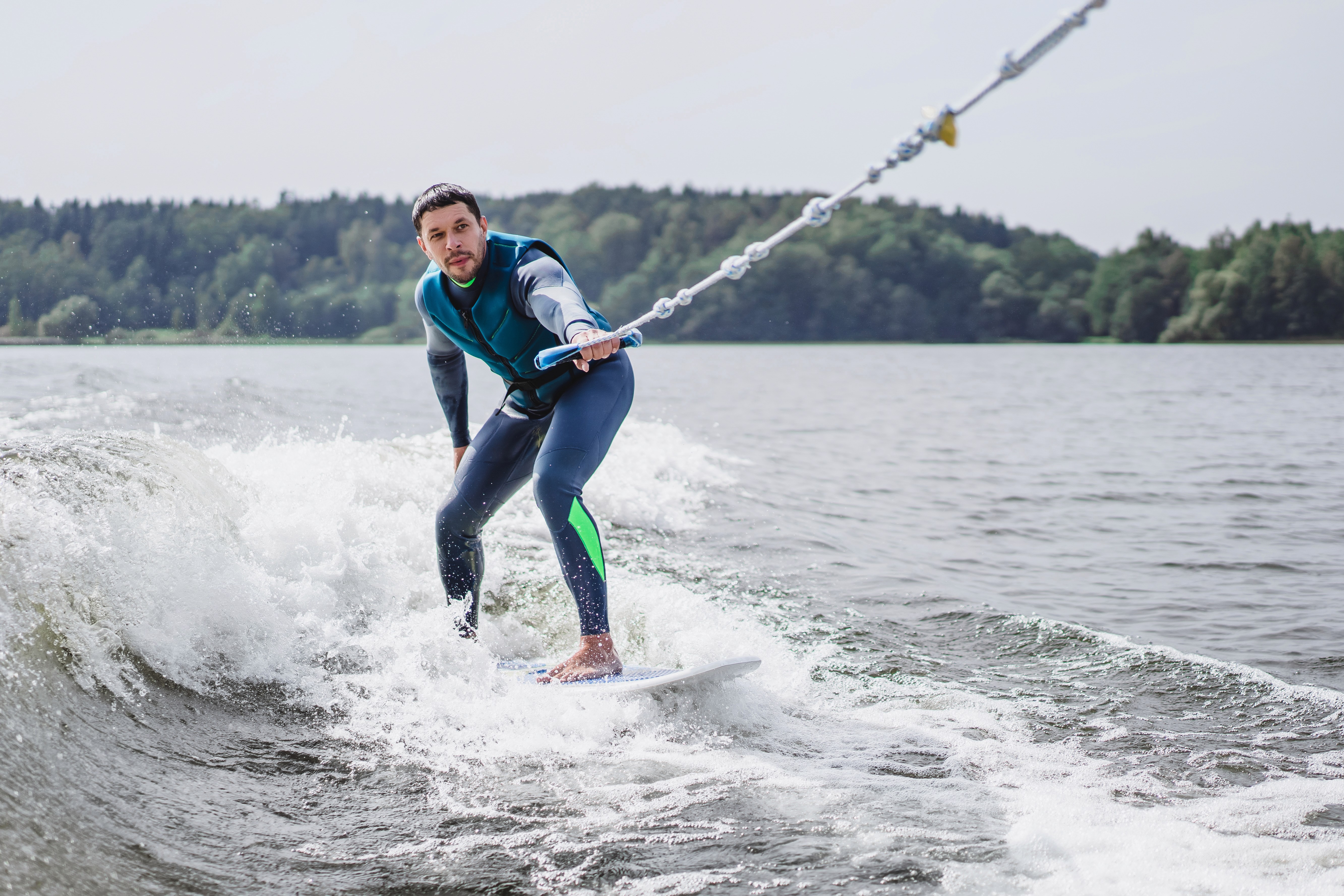 A person rides the waves on a wakeboard while being pulled by a boat.