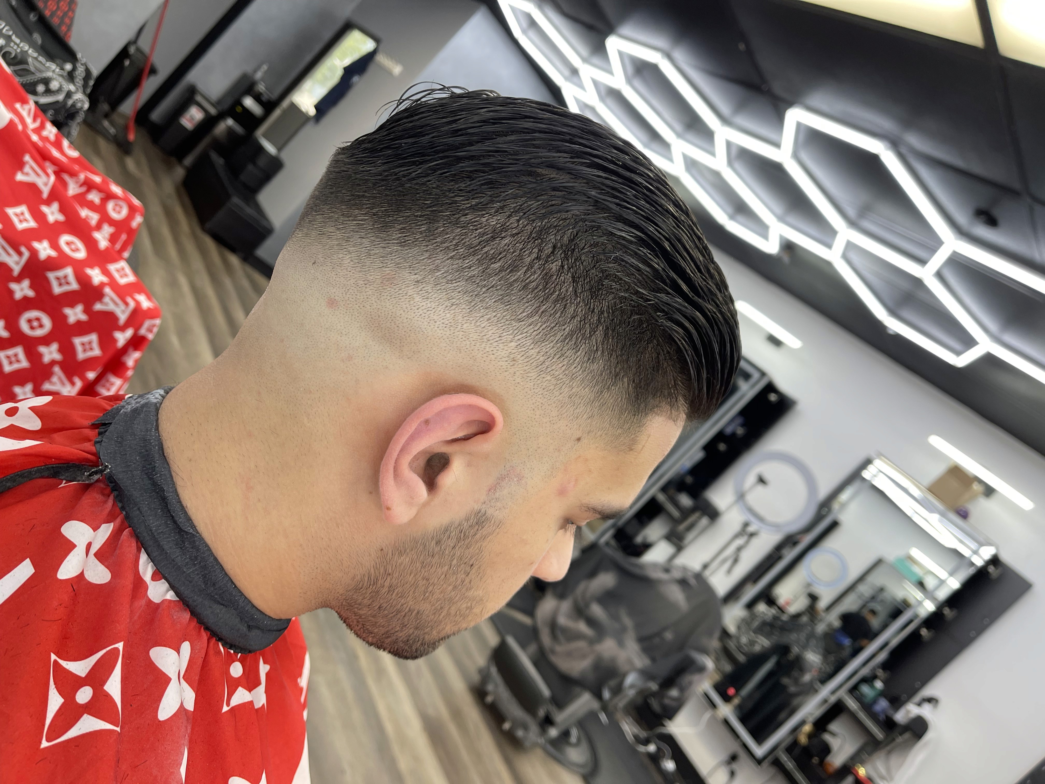 Man with slicked-back hairstyle and mid-to-high skin fade haircut.