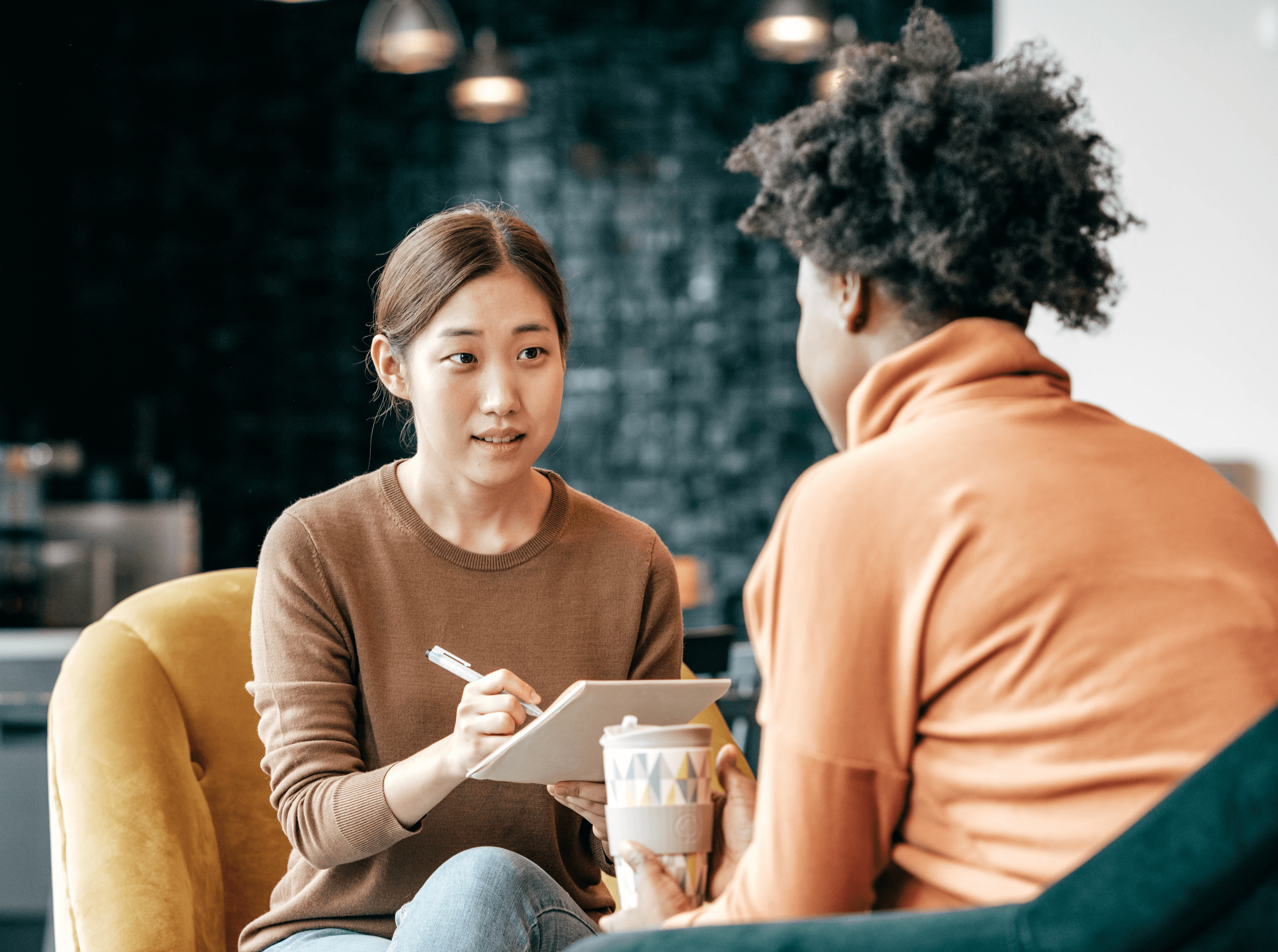 Close-up of a sketchbook showing hand-drawn website wireframes with a phone and pen on the table