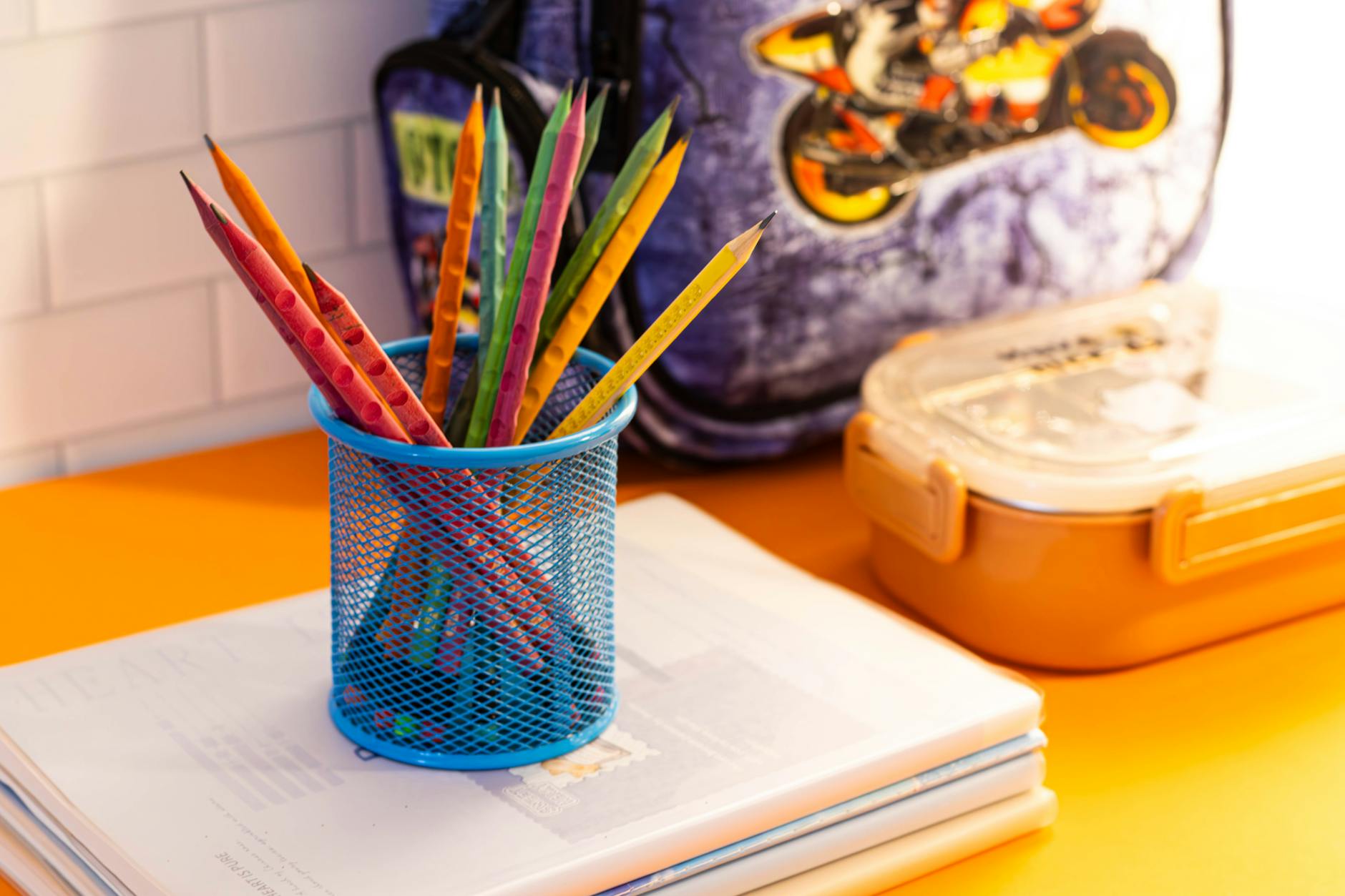 A group of happy children wearing backpacks walk together toward a small community building in a suburban park.