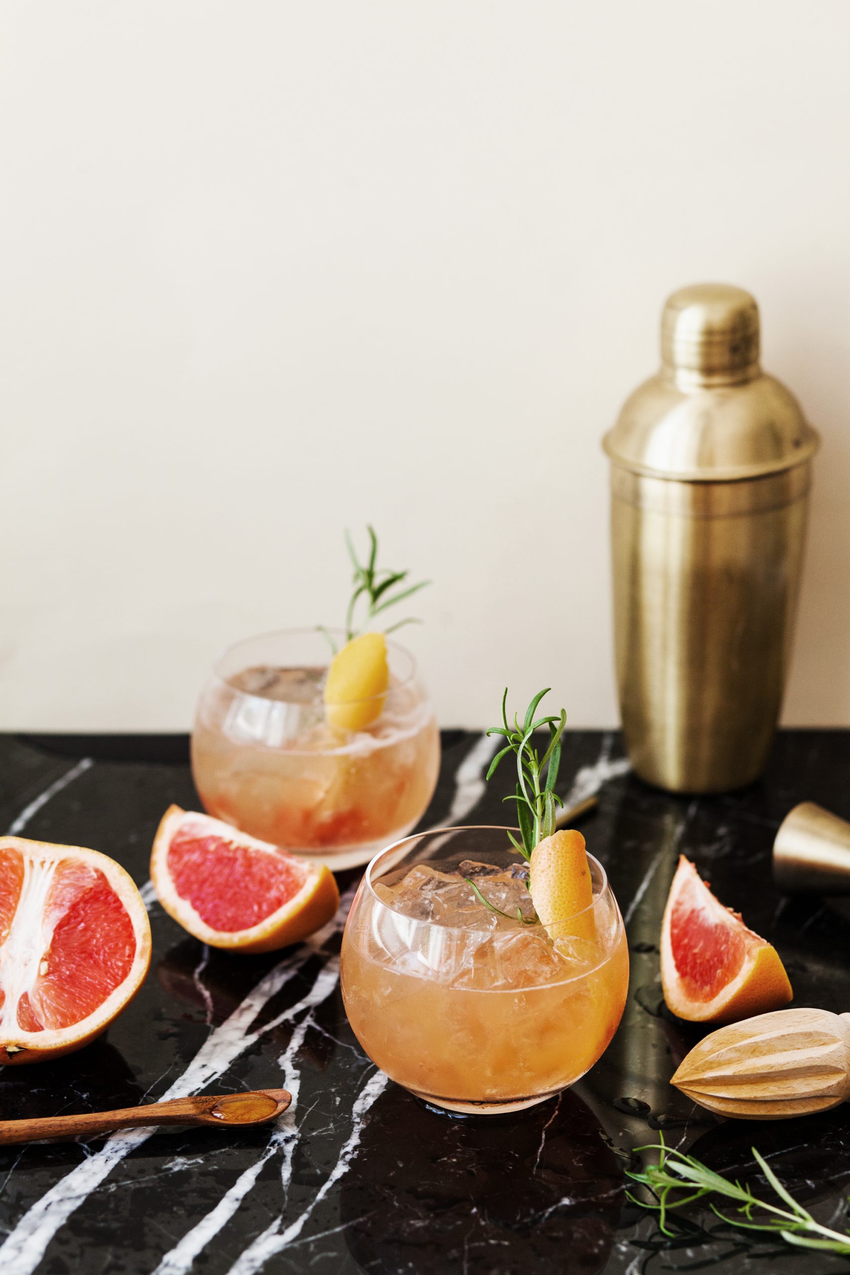 A whisky glass filled with grapefruit segments, honey syrup, Chopin vodka, crushed ice, and garnished—served as a Bitter Honey Bee cocktail.