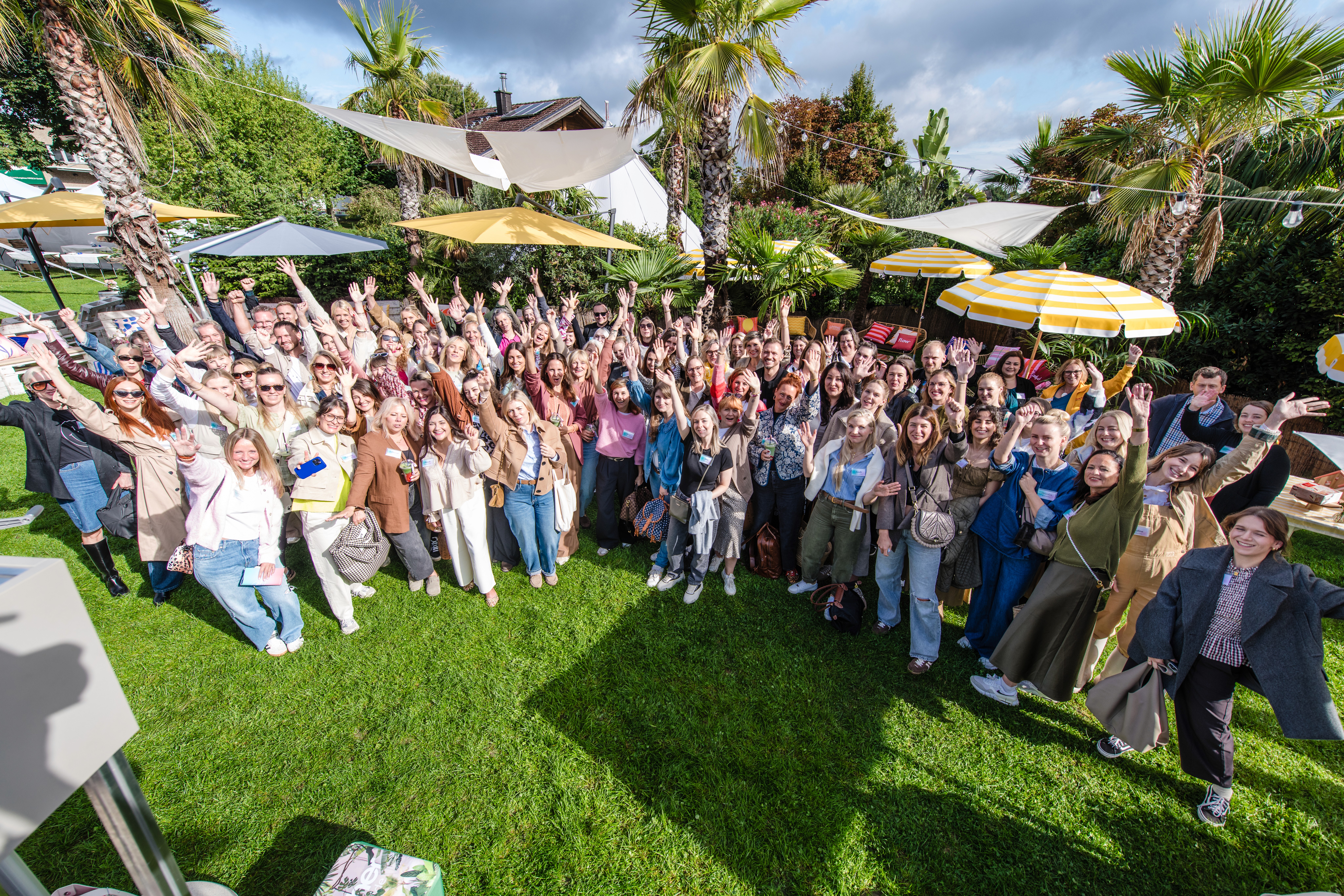 Großes Gruppenfoto von Teilnehmerinnen des Creator Events GHBA & friends im Garten mit Palmen und Sonnenschirmen.