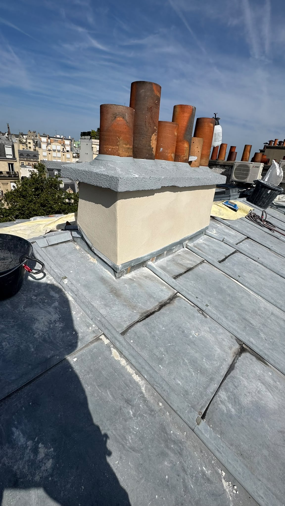 Souche de cheminée enduite et remise en état avec mitrons en terre cuite sur couverture zinc à Paris