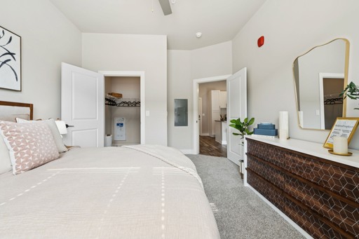 A well-furnished bedroom with a comfortable bed, a stylish dresser, and a mirror enhancing the space's brightness.