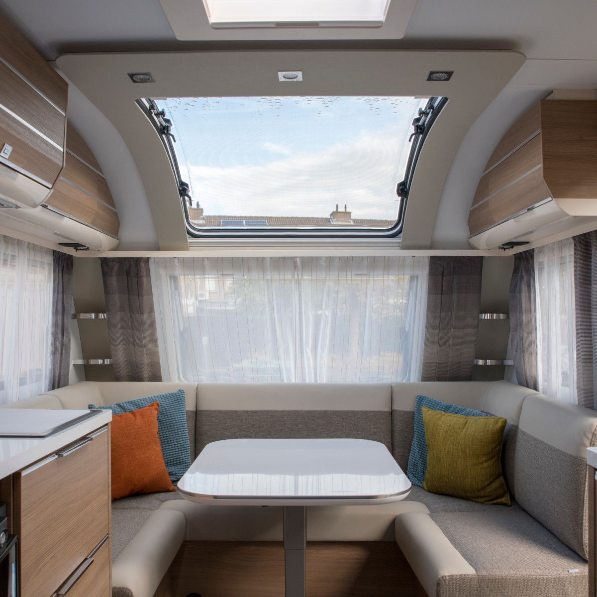 Interiör av en husvagn med, soffor, gardiner och färgglada kuddar 