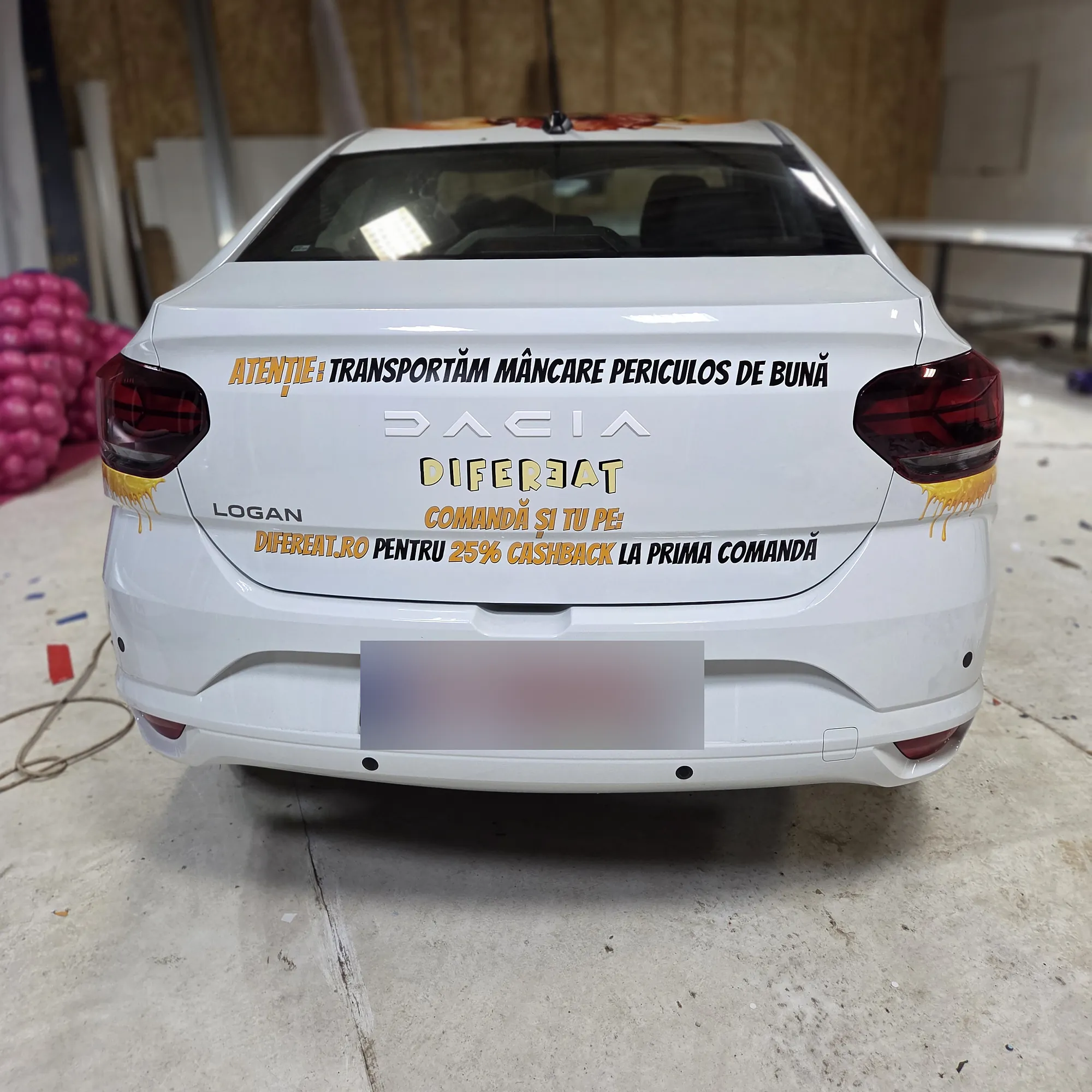 Spatele mașinii Difereat Burgers colantat cu mesajul „Transportăm mâncare periculos de bună”
