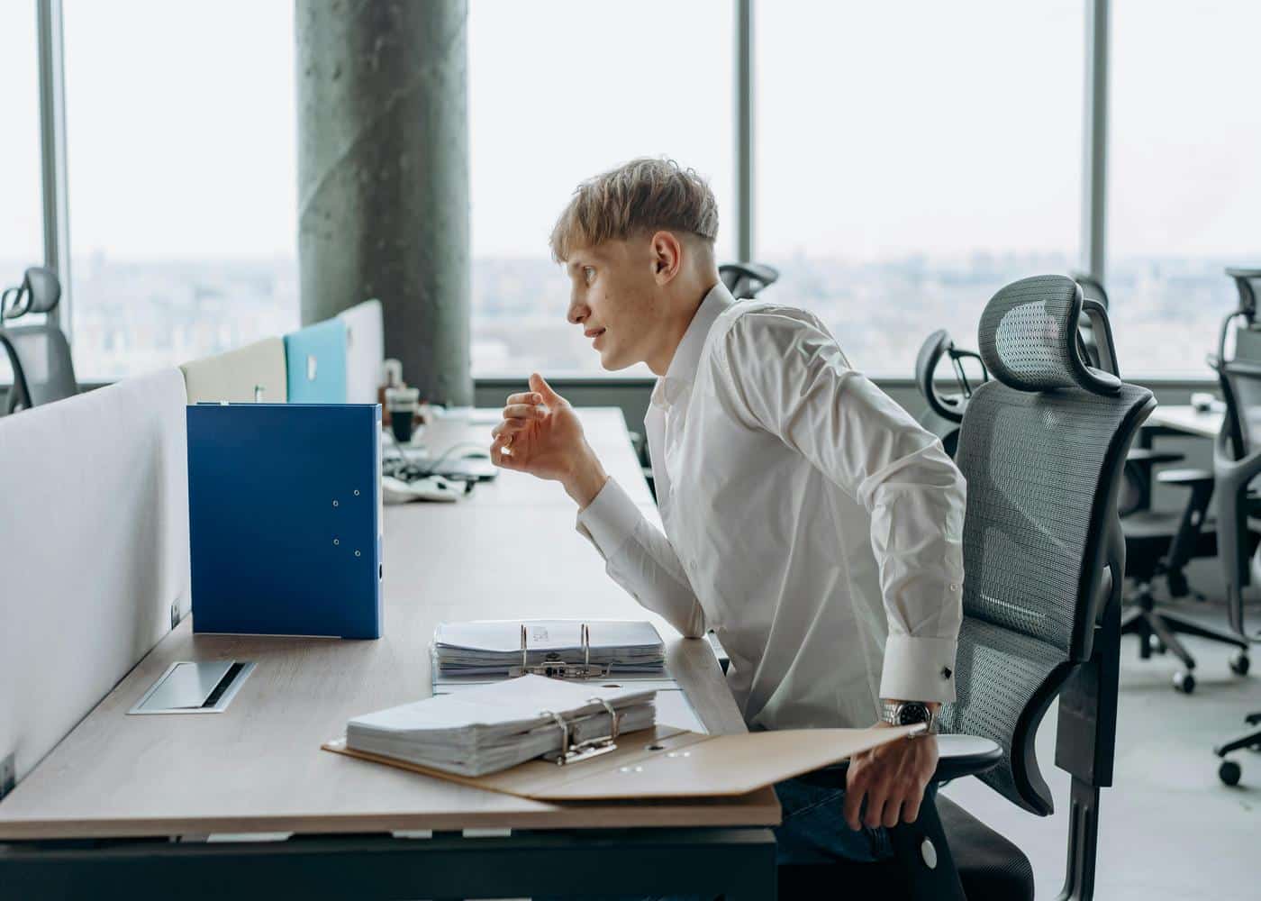 Man sitting on desk attempting to fix posture