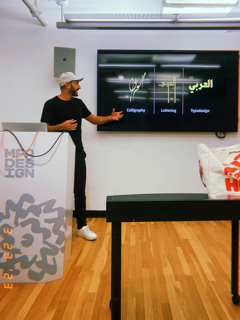 a man giving a lecture at a podium with a large monitor behind him