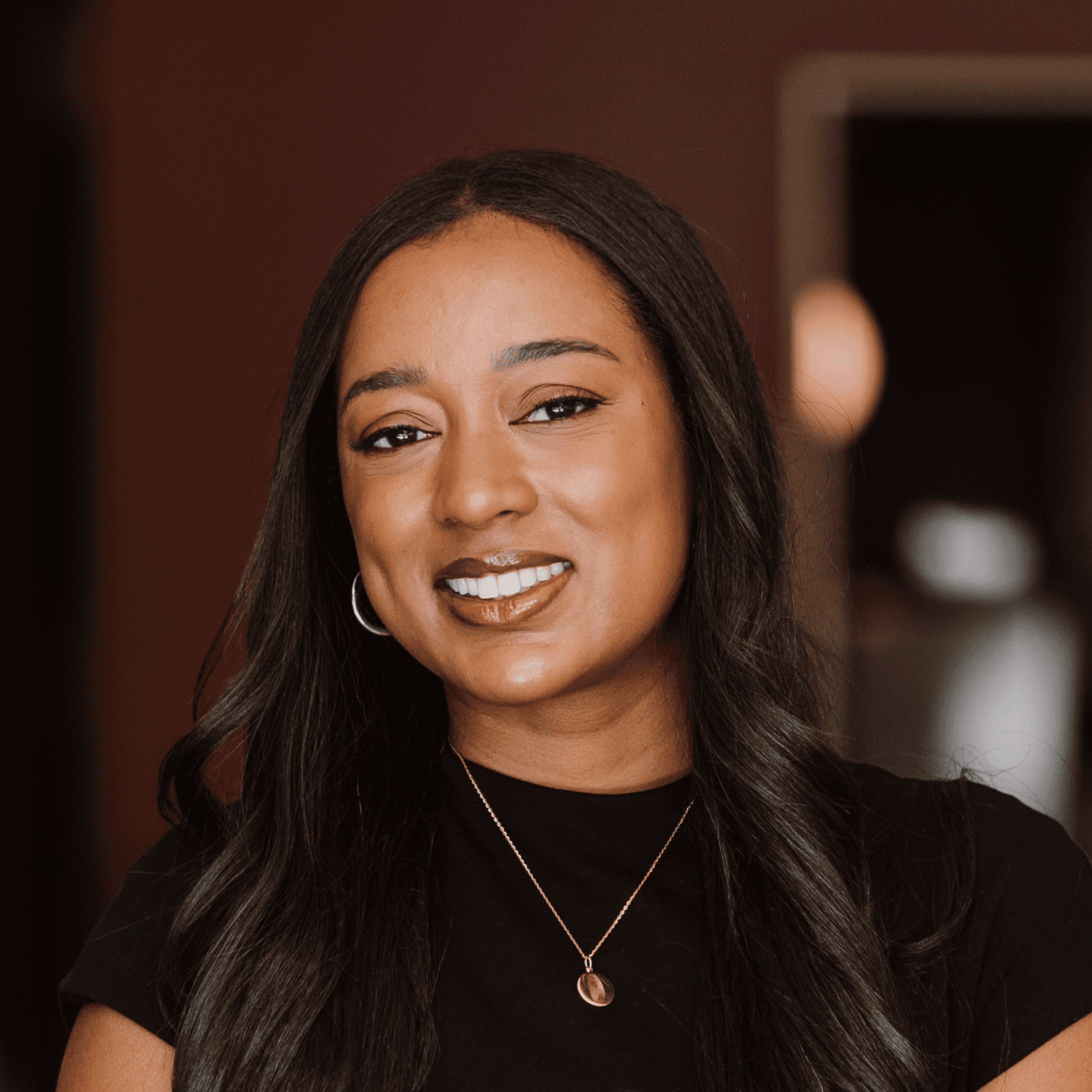 Smiling man with light brown hair and stubble, wearing a khaki shirt in natural light