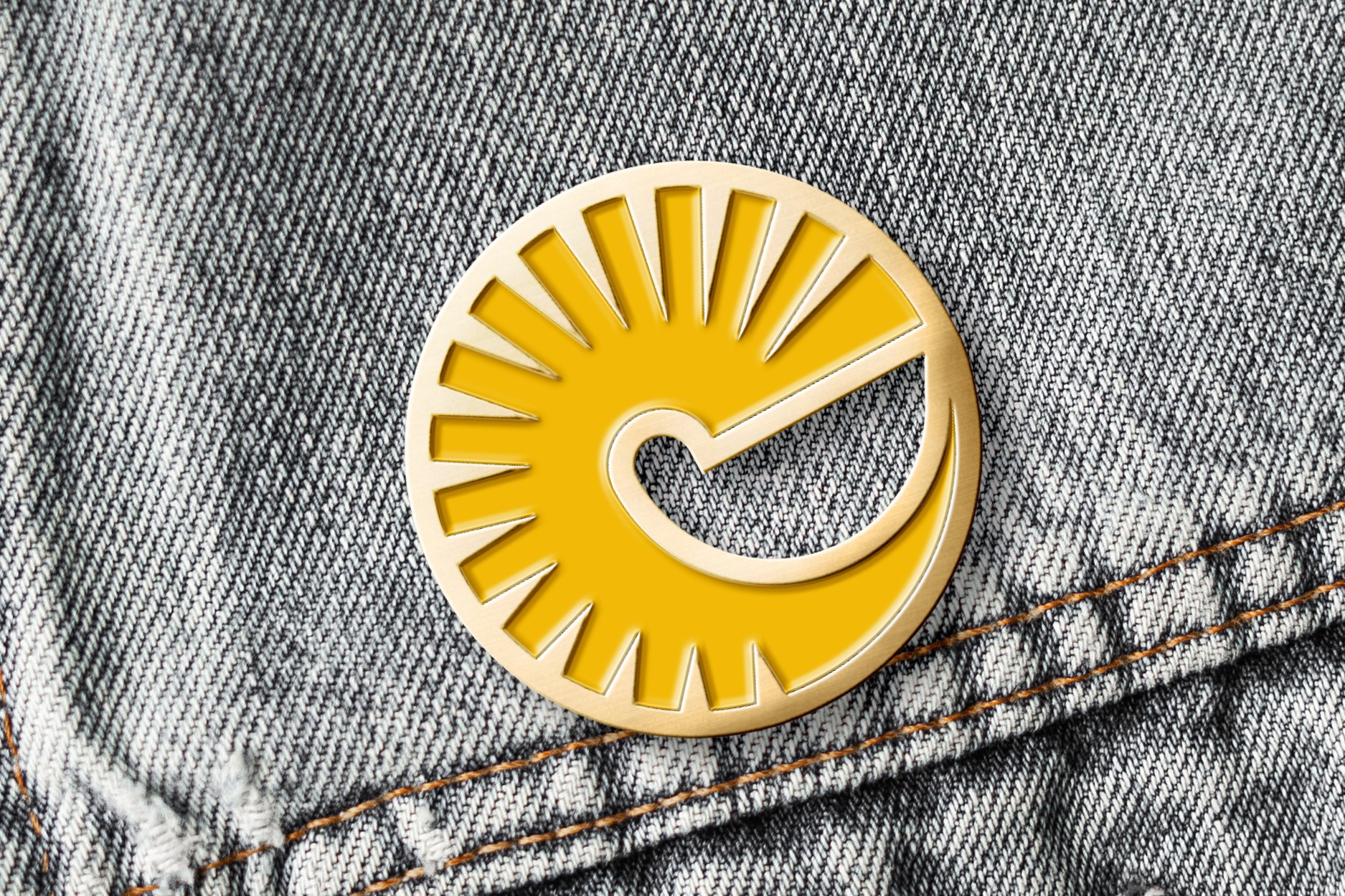 Golden Fleece Films yellow and gold enamel pin featuring the brand symbol, attached to a faded denim jacket.