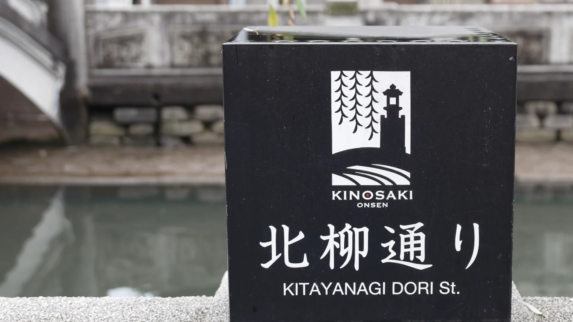 A stone street marker in Kinosaki reading Kitayanagi Dori beneath the town's logo.