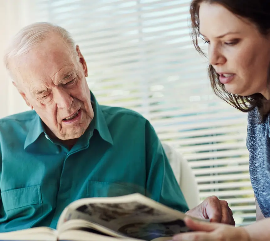 Caregiver supporting an older man with Alzheimer's during a daily activity at home