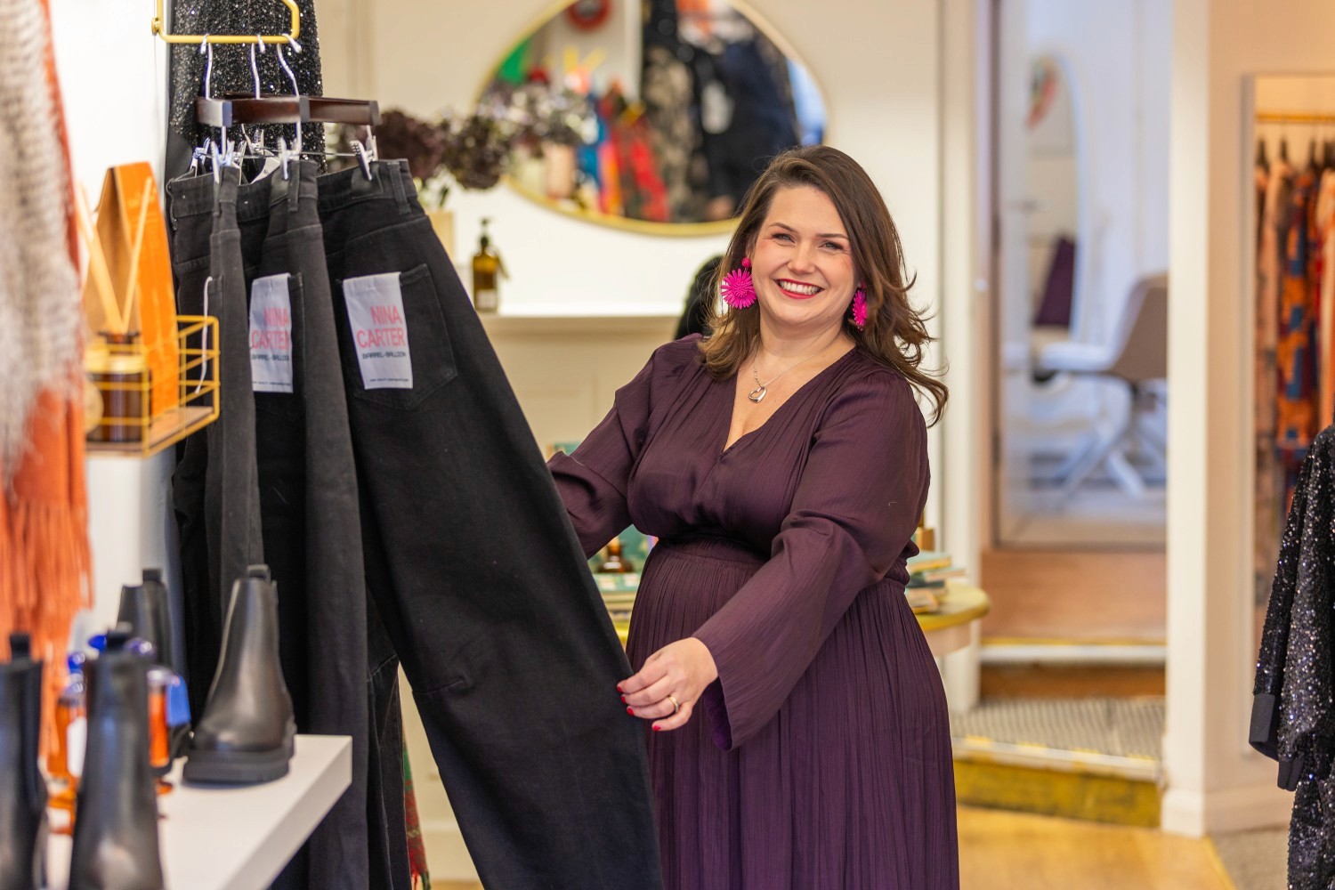 Lucy holding a pair of dark denim jeans