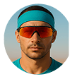 Man in turquoise headband and sunglasses looking straight at the camera. He is wearing red lenses in the glasses.